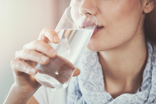 Patient drinking a glass of water as recommended by dental professionals at Watermark Dentistry in Normandy Park, WA